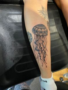 a person with a tattoo on their leg has a jellyfish tattooed on her arm