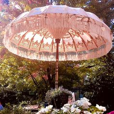 an open umbrella sitting on top of a table in the middle of a garden filled with flowers