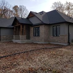 a house that is in the middle of some leaves on the ground and trees behind it