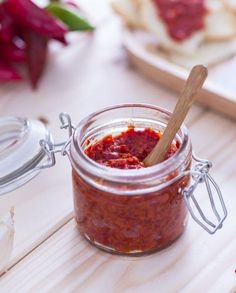 a jar filled with red sauce sitting on top of a wooden table