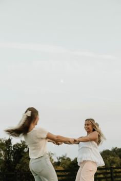 two women are playing with a frisbee in the field