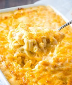 a spoon full of macaroni and cheese being lifted from a casserole dish