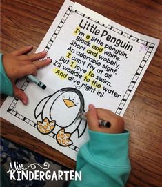 a child's hand writing on a penguin poem