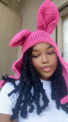 a woman wearing a pink crochet hat with an animal ears on her head