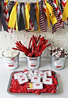 red, white and black candy bars in tins on a table with ribbons hanging from the ceiling