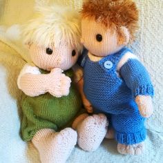 two knitted dolls sitting next to each other on a white blanket, one with blonde hair