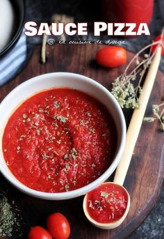 a white bowl filled with sauce next to some tomatoes