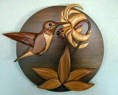 a wooden wall hanging with a bird and flower on it's side, in the shape of a circle