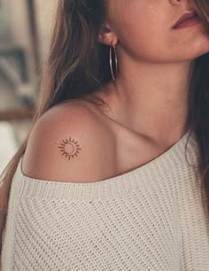 a woman with a small sun tattoo on her shoulder