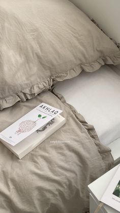 a book sitting on top of a bed next to an open pillow and two pillows