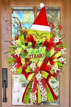 a christmas wreath hanging on the front door with an angry grin face wearing a santa hat