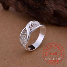 a silver ring sitting on top of a sandy beach next to a tree branch and rock