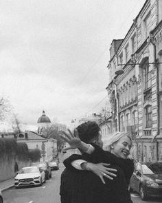 black and white photograph of two people hugging each other on the side of a road