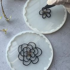 two white plates with black handles and flowers on them, one being cut into smaller pieces