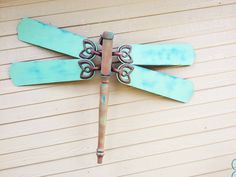 a metal dragonfly sitting on top of a wooden wall