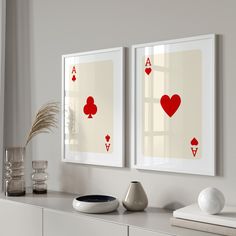 two framed playing cards on a wall next to a vase with a plant in it