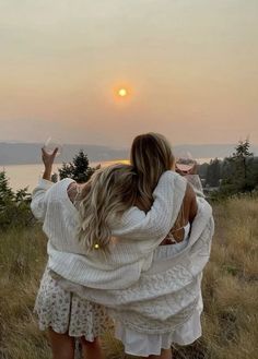 two women hug each other as the sun sets