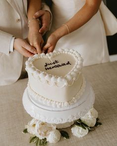 a bride and groom cutting into their wedding cake with the word married written on it