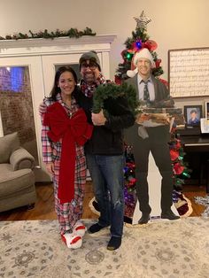 two people standing next to each other in front of a christmas tree with a man and woman