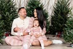 a man and woman are sitting on the floor with their baby