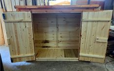 an unfinished wooden cabinet with doors open in a shop or office area, ready to be used as a storage unit