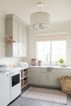 a kitchen with white cabinets and gray flooring, including a washer and dryer