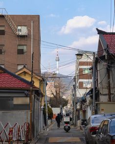 an alley way with cars parked on both sides and people walking down the street in the distance