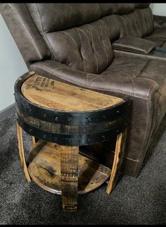 a wooden barrel table sitting on top of a carpeted floor next to a leather couch