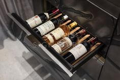 an open drawer holds several bottles of wine