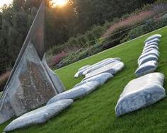 the sun is setting behind some large rocks on the green grass with trees in the background