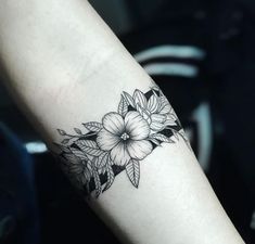 a black and white flower tattoo on the left arm, with leaves around it's edges