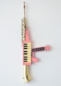 a pink and gold musical instrument is hanging on the side of a white wall,