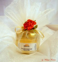 a bottle with a rose on top of it sitting on a white cloth covered table