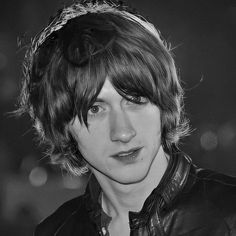 a black and white photo of a young man wearing a leather jacket with his hair pulled back