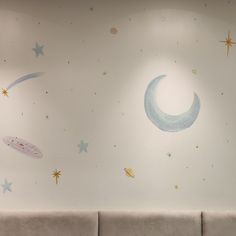 the wall has stars and moon decals on it, along with a couch in front of it