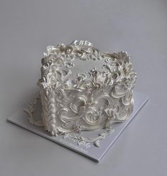 a decorative white cake on top of a gray table with silver trim around the edges