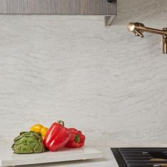 some peppers are sitting on a cutting board next to a faucet in a kitchen