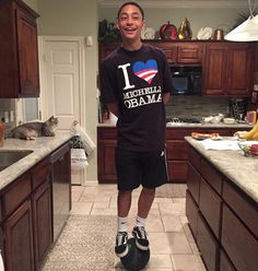 a man standing in the middle of a kitchen with his feet on an object that says i love america