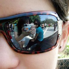 a woman taking a selfie with her cell phone in front of her sunglasses,