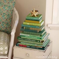 a stack of books sitting on top of a white chair next to a pile of pillows