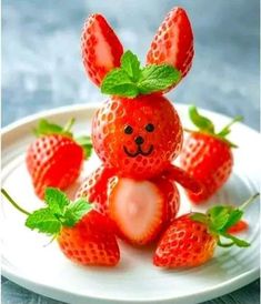 some strawberries are sitting on a plate with a bunny made out of one strawberry