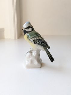 a small figurine of a bird sitting on top of a piece of white marble