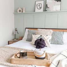 a tray with some coffee cups sitting on top of a bed next to a pillow