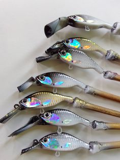 five different types of fishing lures lined up on a white surface with wooden handles