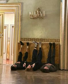 three men laying on the floor in front of a chandelier with their feet up