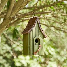 a green birdhouse hanging from a tree branch