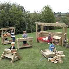 children playing with wooden toys on the grass in an outdoor play area that is made out of pallet wood