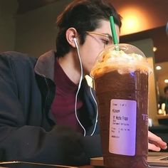 a man sitting at a table with a drink in front of him and headphones on his ears