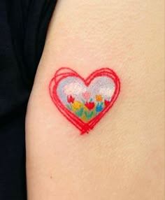 a heart shaped tattoo on the back of a woman's arm with flowers in it