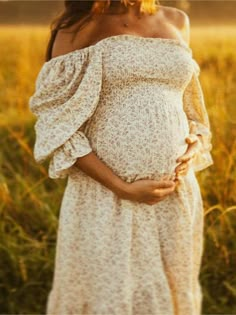 a pregnant woman standing in a field with her hands on her stomach